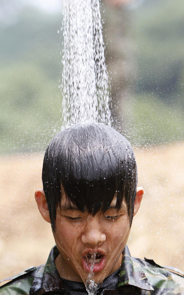 A student participant takes a shower during a summer training course of the Special Warfare Command at the military base in Bucheon, near Seoul, August 4, 2010. About 230 civilian volunteers including middle and high school students participated in the special force\ width=
